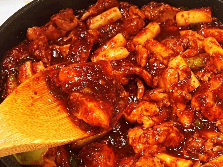 glossy Korean spicy chicken finished with sesame seeds in pan